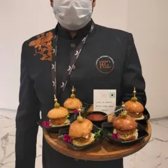A server presenting a tray of Red Sliders with Peri-Peri Mayo. These mini burgers are a crowd-pleasing option for corporate parties and casual gatherings, served with a gourmet twist.