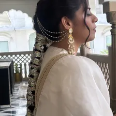 This is a stunning example of a modern bridal braid, heavily embellished with silver mirror-work accessories. The style combines a sleek top with a dramatic, decorated braid, perfect for a sangeet or reception look.