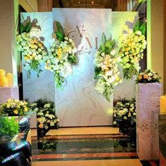 A modern and chic photo backdrop with a marble-finish background, the couple's monogram, and cascading arrangements of white and yellow flowers.