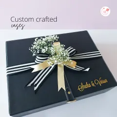 Custom crafted cases that make a statement. This black leather-style box is personalized with the couple's name and finished with a striped ribbon and a sprig of baby's breath.