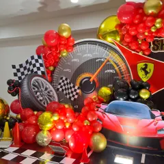 A close-up of the Ferrari decor, highlighting the tire prop, checkered flag, and red and gold balloon clusters.