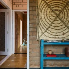 In our EESHA residence project, we used Compressed Stabilized Earth Blocks (CSEB) for the walls. These unburnt mud bricks provide excellent thermal insulation and are a core part of our sustainable building practice. The doorway shown here features a repurposed frame salvaged from a demolished home, giving a new life to old materials.