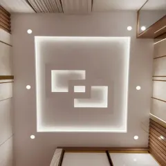 A modern, multi-layered square false ceiling design with integrated cove lighting.