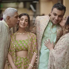 A heartwarming family portrait, with the parents kissing the bride and groom on their cheeks.