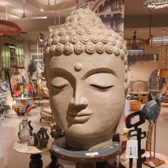 A massive, serene Buddha head sculpture that serves as a powerful and grounding centerpiece in our showroom. We can source similar large-scale artifacts for your project.