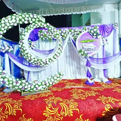 A unique double-moon cradle setup for a naming ceremony. The decor uses white and purple flowers with matching drapes for a coordinated and grand look.