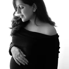 A quiet, contemplative black and white portrait of a mother-to-be. She looks down at her bump with so much love, a moment of pure connection.