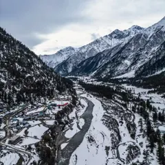 A sweeping aerial view of a snow-covered valley in Spiti, showing the river carving its path through the winter landscape. This is a classic example of Himalayan drone photography, capturing the vastness of the region.