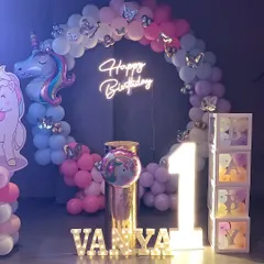 A closer look at the unicorn party backdrop, focusing on the neon sign, marquee letters, and "BABY" blocks.