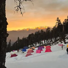 Camping in the snow under a fiery sky. This is our campsite at Juda ka Talab on the Kedarkantha trail, where you get to witness incredible sunsets over the mountains.