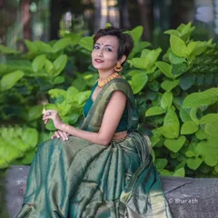 A wider shot of the model in the green saree, seated in a park. This image highlights how traditional wear can be styled for a modern, everyday context.