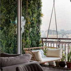 A view from the living room to the balcony, showing the inviting swing against the backdrop of the city. The green wall creates a private, garden-like feel.