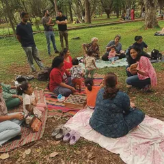 Reading a storybook to an attentive group of toddlers and parents. You can see the mix of ages and the comfortable, casual setting that makes our Cubbon Park storytelling sessions so special for the whole family.