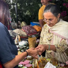 I always believe you should taste the quality for yourself. Here I am at a market, offering a sample to a customer. It brings me joy to see people enjoy the food I make.