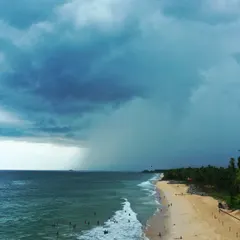 A dramatic aerial photo of a rainstorm approaching Kapu beach. This image captures the sharp contrast between the sunny shore and the dark, imposing storm clouds, a testament to being ready for any weather.