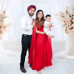 This family portrait stands out with a bold splash of red. The mother's elegant gown and the happy baby create a truly memorable and stylish image.