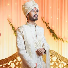 A classic portrait of the groom in his wedding attire. His elegant sherwani, pearl necklace, and feathered safa (turban) create a look of timeless royalty.