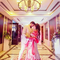 A dramatic, wide-angle shot of a couple in a beautifully lit hotel corridor. I use architectural elements and perspective to frame the couple, creating a grand and romantic portrait that feels like a scene from a movie.