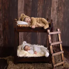 An artistic and heartwarming newborn portrait of twins, each sleeping peacefully in their own level of a miniature wooden bunk bed. This shot highlights our creative and safe approach to capturing your baby's first precious moments.
