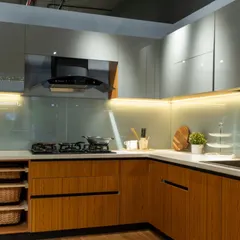 A closer look at the combination of natural wood-textured cabinets and a light grey lacquered glass backsplash. The under-cabinet lighting enhances the warmth of the wood and provides excellent task lighting for the countertop.