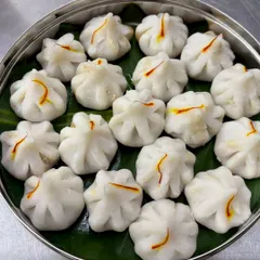 Nothing says celebration like homemade Modak. For Ganesh Chaturthi, we prepare these delicate steamed rice-flour dumplings filled with a sweet mixture of coconut and jaggery. Each one is carefully shaped by hand and topped with a strand of saffron, made just the way my dadi taught me.