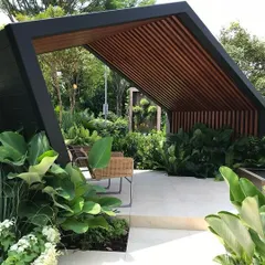 The architectural gazebo in this garden serves as a perfect outdoor living room. We surrounded it with large-leafed plants like Philodendron to create a sense of enclosure and privacy.