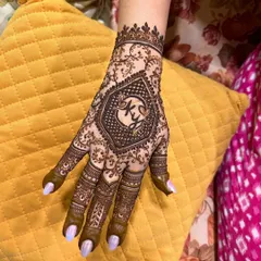 A close-up of a personalized engagement mehendi. The bride's hand features a hexagon with the couple's initials, "K" and "Y", at the center.