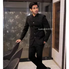 A client wearing a classic black Jodhpuri suit with subtle, sparkling black beadwork on the shoulders. This is a perfect outfit for a cocktail night or reception.