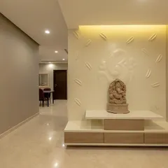 A serene pooja area designed right at the entrance of an apartment. The backdrop features a subtle, 3D Ganesha relief, creating a peaceful and spiritual focal point.
