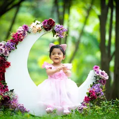 A magical moon prop set against a lush, green forest backdrop. This photo shows how we can bring creative studio elements outdoors for a truly unique look.