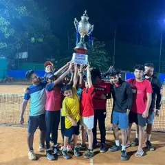 The ultimate moment of victory in our Tennis Temple Premier League. A team celebrates hoisting the championship trophy under the floodlights, capturing the spirit of competition and teamwork that defines our league.