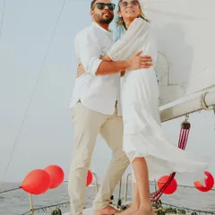 A stylish pre-wedding portrait on a sailboat. The wind in her dress and the open sea behind them create a sense of freedom and adventure, perfect for couples who want a unique and memorable shoot.