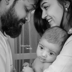 An intimate black and white close-up of a new family. The parents' foreheads touch as they admire their baby, creating a sense of a private, love-filled world.