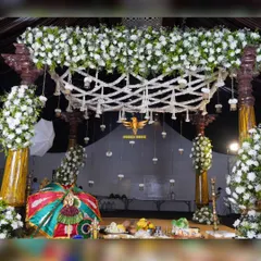 A traditional bell mantap designed for a Muhurtham ceremony. The structure is adorned with beautiful white flowers and intricate details, creating a sacred and stunning centerpiece for the wedding.
