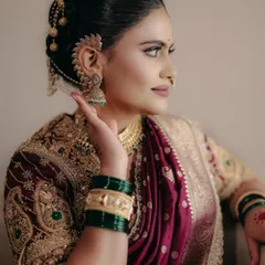A beautiful profile shot of a Maharashtrian bride. The makeup is bold yet soft, with defined eyes and radiant skin. The look is completed with a traditional nath and hair accessories, celebrating fierce femininity.