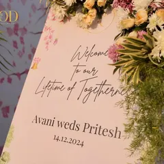 A beautiful welcome sign for Avani and Pritesh, with elegant calligraphy and a soft floral design, perfectly complemented by a lush flower arrangement.