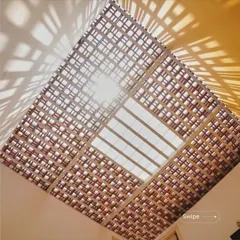 A view looking up at the skylight in the Raghavendra Residence. The terracotta jali creates a beautiful geometric pattern against the sky, filtering the harsh sun and casting artistic shadows on the bright yellow wall below.
