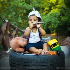 This creative "little mechanic" themed photoshoot for a toddler was set up outdoors. We used a variety of props like a tire, tools, and toys to build a fun and playful scene that captures his curious personality.