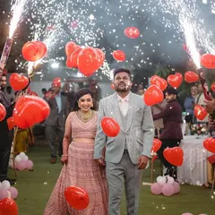 Your walk-in should be a celebration. Here, we created a path of joy with friends holding red heart balloons and cold sparklers, making the couple's entry feel vibrant and full of love.
