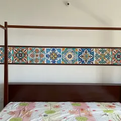 This wall mural above a bed features hand-painted Moroccan tile patterns, adding a touch of ethnic charm and vibrant colour to the bedroom.