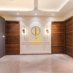 This hallway features a stunning accent wall with white molding and contemporary gold sconces. The rich wooden doors on either side provide a warm contrast, showcasing our attention to detail in transitional spaces.