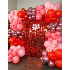 For a touch of glam, this Valentine's setup includes a shimmering red sequin wall. It's framed by a garland of red and pink balloons with a "Be Mine" sign, perfect for a fun party.