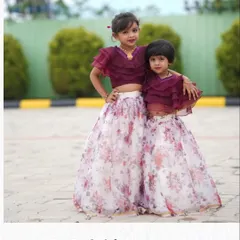 Sisters twinning in custom lehengas. I made these outfits with a floral organza skirt and a ruffled wine-colored crop top.