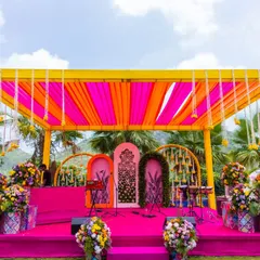 Welcome to Rangeela Rajasthan! We love creating immersive themes, and for this Mehendi, we transformed an outdoor space into a vibrant carnival with bright pink and yellow drapes, traditional Rajasthani decor, and a stage ready for folk music and dancing.