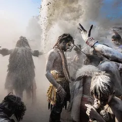 A wider view of the Masan Holi celebration, showing the chaotic dance amidst clouds of ash from the cremation grounds. The scene is painterly and full of movement.