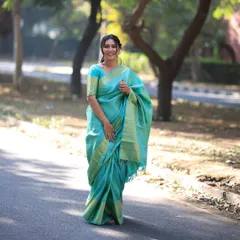 A full-length view of this graceful pooja look. The turquoise silk saree is expertly draped to create a flattering silhouette, paired with a simple, elegant hairstyle.