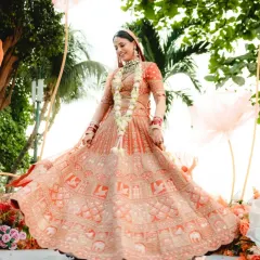 A radiant bride twirling in her stunning orange lehenga. This full-length shot captures the beautiful movement and detail of her outfit.