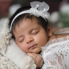 An even tighter close-up on the baby's face, highlighting the delicate headband and her perfectly peaceful expression.