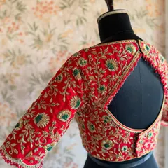 This red bridal blouse features a classic round keyhole back, bordered with heavy zardozi embroidery that matches the work on the sleeves.