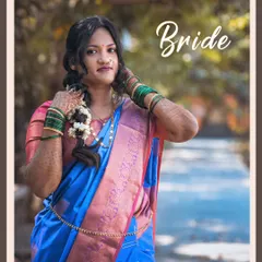 A model portfolio shot showcasing a traditional Maharashtrian bridal look. The blue and pink saree, green bangles, and classic hairstyle are captured in soft, natural light.